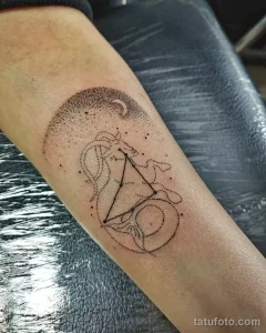 Фото татуировки Козерога и луны на руке, выполненной в технике dotwork. Изображение состоит из множества точек, создающих эффект градиента и объема.