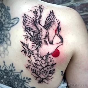 Фото тату цапли в стиле dotwork с цветами и ветками на спине. Рисунок выполнен черными точками и линиями.