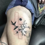 Черно-белое фото тату на бедре с изображением летящего ворона, цветущей ветви сакуры и геометрических фигур.