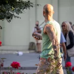 Фото татуировки на руке мужчины, выполненной в технике блэкворк. Рисунок покрывает часть руки, на фоне красных роз.