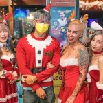 Фотография четырех девушек в рождественских нарядах с татуировками на теле. Праздничная атмосфера и яркие образы.