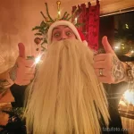 Фото мужчины в костюме Деда Мороза с татуировками на руках. Веселый образ, татуировки на предплечьях.