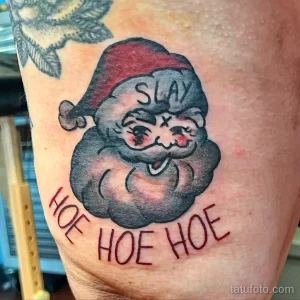 Фото татуировки Санта Клауса с надписью "Slay Hoe Hoe". Необычный и провокационный дизайн.