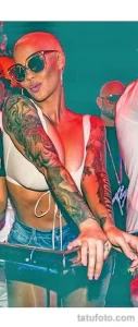 Фото тату: Amber Rose с яркими татуировками на руке, включая изображения цветов и абстрактные узоры. Иллюстрация для поиска идей тату в стиле акварель.