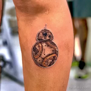 Фото тату: изображение дроида BB-8 из Звездных войн, выполненное в черно-серых тонах на ноге. Детализированный рисунок с акцентом на округлые формы.