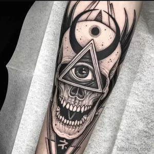 Фото тату: татуировка в стиле blackwork с изображением черепа, глаза в треугольнике и мистических символов на руке.
