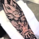 Фото тату на руке: реалистичное изображение персонажа Гоку из аниме Dragon Ball. Черно-серые тона, высокая детализация, мужская рука.