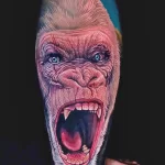 Фото тату гориллы на руке. Реалистичная татуировка с изображением рычащей головы гориллы. Яркие цвета и детализированная проработка.