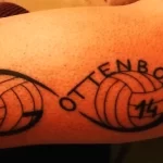 Фото татуировки на плече с двумя волейбольными мячами и надписью "OTTENBORG 14". Рисунок выполнен в черном цвете, с четкими линиями и цифрами.