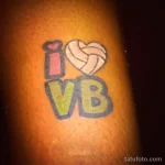 Фото тату: красочный рисунок волейбольного мяча и надписи 'I ❤️ VB' на руке. Веселая и позитивная татуировка для любителей волейбола.