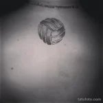 Фото минималистичной татуировки волейбольного мяча, выполненной в оттенках серого на животе.
