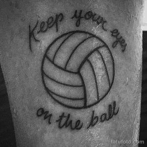 Фото простой татуировки волейбольного мяча с надписью 'Keep your eye on the ball'. Черно-белый рисунок татуировки на руке.