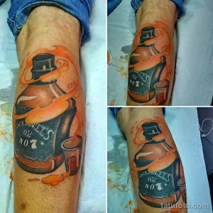 Фото тату яркой бутылки виски Jack Daniel's на ноге. Детализированный рисунок с использованием насыщенных цветов и теней.