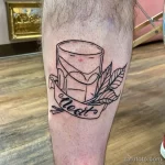 Черно-белая татуировка на ноге с изображением стакана и надписи 'Neat'. Лаконичный рисунок в стиле лайнарт.