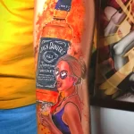Фото тату на руке: яркая и красочная татуировка с изображением бутылки Jack Daniel's и девушки в стиле пин-ап.
