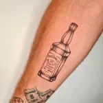 Фото тату на руке: минималистичный контурный рисунок бутылки виски Jack Daniel's, выполненный в черном цвете.