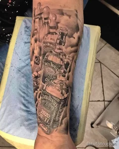 Фото тату сложного рукава с изображением бутылок Jack Daniel's, кеглей для боулинга и других элементов, выполненного в реалистичном стиле с высокой детализацией.