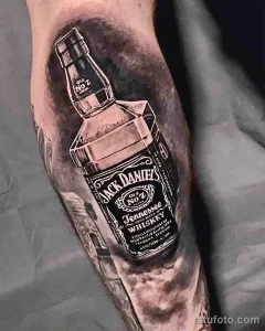 Крупный план татуировки на руке, изображающей бутылку виски Jack Daniel's с детальной проработкой этикетки и теней.