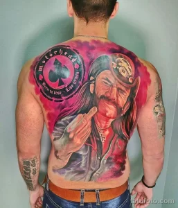 Фото татуировки на спине: реалистичный портрет Лемми Килмистера из Motörhead с логотипом группы и яркими красками.