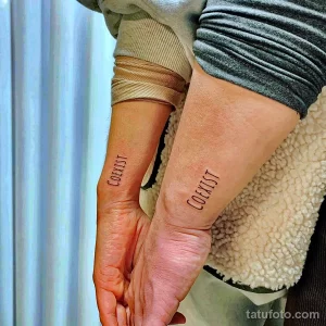 Фото парных тату с надписью "Coexist" на запястьях. Простой, но мощный символ призыва к миру и взаимопониманию.
