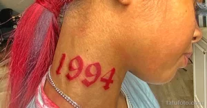Фотография татуировки с годом рождения '1994' на шее девушки. Татуировка выполнена в красном цвете в стиле олдскул.