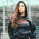 Фото тату: девушка с яркой татуировкой дракона на шее и плече. Дракон изображен в ярких красных и желтых тонах, с детализированными чешуей и когтями.