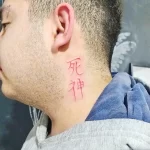 Фото тату: красные китайские иероглифы на шее мужчины. Минималистичный рисунок татуировки.
