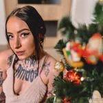 Фото тату на теле девушки: грудь, плечи и руки покрыты татуировками в стиле олдскул и графика.