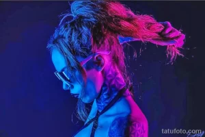 Фото тату: девушка с неоновой татуировкой на шее и плече, выполненной в синих и розовых тонах. Современный и стильный рисунок татуировки.