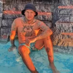 Фото тату на теле мужчины: якорь, ласточки, череп и красочные брызги краски в морском стиле. Детализированный рисунок татуировки.