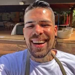 Фото мужчины с татуировками на лице, шее и руках. Татуировки выполнены в черном цвете и имеют геометрический характер. Стильный образ.