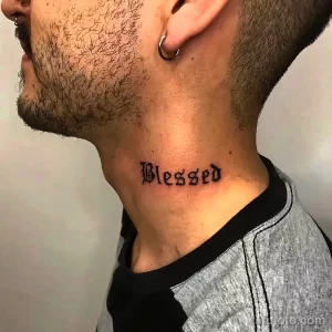 Фото тату надписи 'Blessed' на шее мужчины. Черный шрифт в готическом стиле, выполненный четкими линиями. Минималистичный и эффектный дизайн.