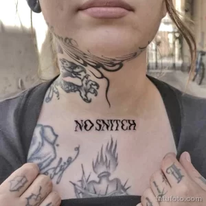 Фото тату: черно-серая татуировка волка и надпись "No Snitch" на шее женщины. Рисунок татуировки в стиле олдскул.