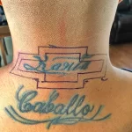 Фото старой татуировки на шее мужчины. Татуировка представляет собой имя "Sam Caballero", выполненное в синем цвете.