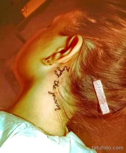 Фото минималистичной татуировки на шее женщины. Надпись 'Enjoy the journey' выполнена тонким шрифтом.