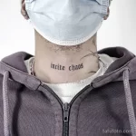 Фото тату: надпись "incite chaos" на шее мужчины. Черно-белый рисунок, готический шрифт, минималистичный стиль.