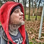 Фото тату: мужчина с обширной татуировкой, покрывающей шею, лицо и часть головы. Черно-белый рисунок, сложный узор, брутальный стиль.