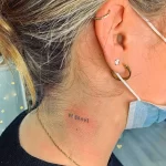 Фото тату: небольшая надпись 'BE BRAVE' на шее девушки. Минималистичный рисунок татуировки.