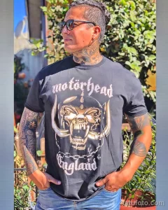 Фото татуировки Motorhead на груди и руках мужчины. Изображение головы War-Pig и логотипа группы в реалистичном стиле.