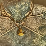 Фото тату на теле мужчины, покрытом сложными геометрическими и органическими узорами. Золотые цепи и кулон дополняют образ.