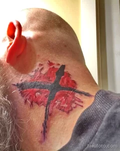 Фото татуировки птицы в стиле акварель на шее мужчины. Рисунок выполнен в ярких красных и черных тонах с использованием размытых красок.