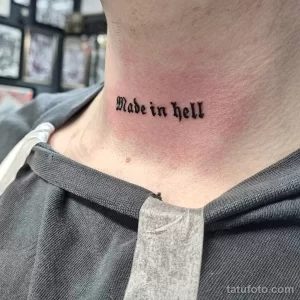 Фото татуировки надписи 'Made in hell' на шее мужчины. Рисунок выполнен в классическом стиле с использованием черных чернил.