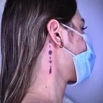 Фото тату с изображением луны, звезд и стрел на шее девушки. Минималистичный и изящный дизайн.