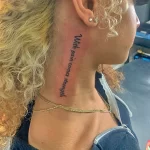 Фото тату: вертикальная надпись 'With pain comes strength' на шее женщины. Черно-белое изображение, минималистичный стиль.