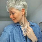Женщина с татуировкой в виде облаков и надписью 'Inhale' на ключице и шее.