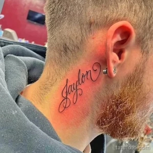 Черная татуировка с именем 'Jaylon' каллиграфическим шрифтом на шее мужчины с бородой.