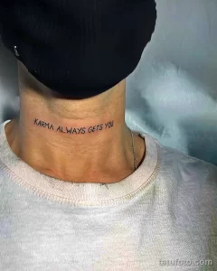 Черная татуировка с надписью 'Karma Always Gets You' вдоль шеи мужчины в черной шапке.