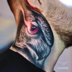 Фотография реалистичной татуировки глаза дракона на шее мужчины. Глаз дракона изображен с детальной проработкой зрачка, радужки и чешуи.