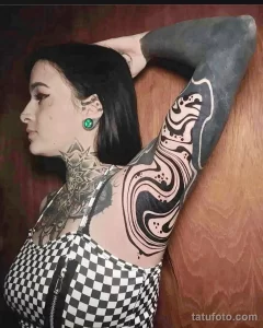 Фото тату: абстрактный рисунок в стиле blackwork на руке девушки, с плавными линиями и геометрическими формами.