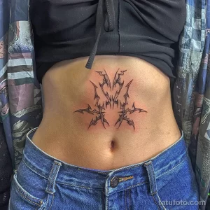 Фото тату: абстрактные линии на животе, выполненные в технике blackwork. Женский эскиз тату с необычной композицией.